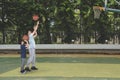 Child learning to shoot a basketball with his father