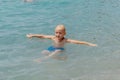 Child learning to swim in the open sea of tropical resort. Kids learn swimming. Exercise and training for young children