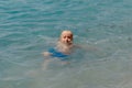 Child learning to swim in the open sea of tropical resort. Kids learn swimming. Exercise and training for young children