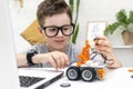 Child learns coding and programming on a laptop. Boy looks with concentration at the robot car and fixes the control Royalty Free Stock Photo
