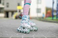 The child learns rollerblading in the yard. Girl in pink tights. Childhood and hobby concept