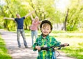 The child learns to ride a bike with his parents in the park