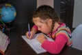 A child learns to write in a notebook. Kid do her homework. The concept of home education in quarantine. A little girl is trying