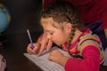A child learns to write in a notebook. Mom helps her daughter do her homework. The concept of home education in quarantine. A Royalty Free Stock Photo