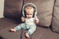 Child learns the world. A little happy child is sitting on bed in big headphones and listening to music