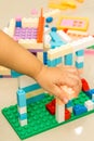 A child left hand playing with colorful plastic bricks at the tile floor Royalty Free Stock Photo