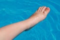 Child leg with foot half submerged in blue swimming pool water Royalty Free Stock Photo