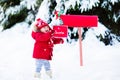 Child with letter to Santa at Christmas mail box in snow Royalty Free Stock Photo