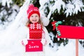 Child with letter to Santa at Christmas mail box in snow Royalty Free Stock Photo