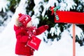 Child with letter to Santa at Christmas mail box in snow Royalty Free Stock Photo