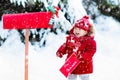 Child with letter to Santa at Christmas mail box in snow Royalty Free Stock Photo