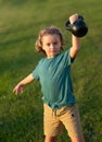 Child lifting the kettlebell in backyard outside. Cute child boy pumping up arm muscles with kettlebell. Fitness kids