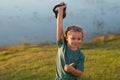 Child lifting the kettlebell in backyard outside. Kids sports exercises. Healthy kids life and sport concept. Portrait