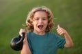 Child lifting the kettlebell in park outside. Sport activities at leisure with children. Sporty kid boy holding Royalty Free Stock Photo