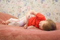 Child little baby girl lying on bed with smartphone in hands.