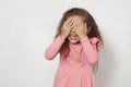 Child little girl covering her eyes by hands against white background Royalty Free Stock Photo