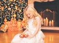 Child little girl with gift box near christmas tree and fireplace home Royalty Free Stock Photo