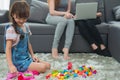 child a little girl is playing blocks at home. Mother with friend working on laptop or shopping online Royalty Free Stock Photo