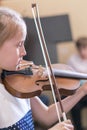 Child, little girl playing violin indoors in music class. vertical photo Royalty Free Stock Photo