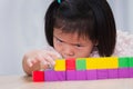 Child little girl playing wooden toys at home or kindergarten school. Kid is seriously sorting and building the wooden blocks. Royalty Free Stock Photo