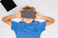 Child liying on bed with 3D Virtual Reality, VR cardboard glasses