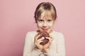 Child llittle girl holding donut on pastel pink background