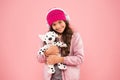 Child long curly hair. cosy winter season. pet care. warm clothes for cold weather. happy little girl play dog toy. pink Royalty Free Stock Photo