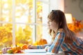 Child at window in autumn. Kids at home in fall Royalty Free Stock Photo