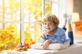 Child at window in autumn. Kids at home in fall Royalty Free Stock Photo