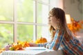 Child at window in autumn. Kids at home in fall Royalty Free Stock Photo