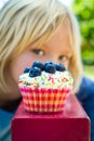 Child looking at tempting cupcake treat. Cupcake in focus.