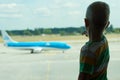 The child looks at the plane through the window of the airport. Royalty Free Stock Photo