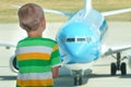 The child looks at the plane through the window of the airport. Royalty Free Stock Photo