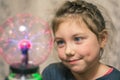 The child looks at the plasma ball. Portrait of a little girl with a magic ball. Kid plays witchcraft and magic