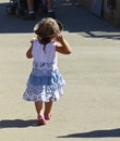 Toddler female child walking along the sidewalk of a county fair