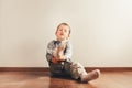 Child with lots of independence sitting on the floor putting on his socks with an expression of effort