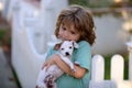 Child lovingly embraces his pet dog. Cute kids playing with chihuahua mixed dog lying on backyard lawn. Carefree Royalty Free Stock Photo