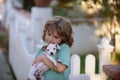 Child lovingly embraces his pet dog. Cute kids playing with chihuahua mixed dog lying on backyard lawn. Carefree Royalty Free Stock Photo
