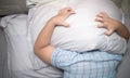 Child lying in bed covering head with pillow Royalty Free Stock Photo