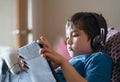 Child lying on couch wearing headphone listening to music, Close up face Kid sitting on sofa watching cartoons on tablet,Young boy Royalty Free Stock Photo