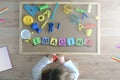 Child lying down on the floor playing with some cube letters composing the word IMAGINE.