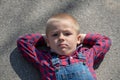Child lying on the floor on back, looking long way off. thoughtful boy portrait lying on crossed arms look into the distance Royalty Free Stock Photo