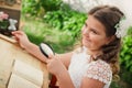 child with magnifying glass near an open book sits at desk in a classroom outdoors on background of green grass