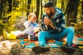 Child makes a cure for the common cold in autumn park. Father and son playing in the autumn forest. Dad and son in the