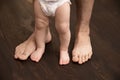 The child makes the first step. Large male legs with small baby legs. Dad helps the child take the first steps