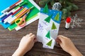 The child makes a greeting card Christmas. Made with his own hands. Children`s art project craft for kids. Royalty Free Stock Photo