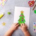 The child makes a greeting card Christmas paper collage. Children`s art project craft for kids Royalty Free Stock Photo