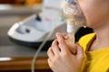 Child makes inhalation at home with nebulizer on out of focus background