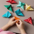 A child makes origami figures. Children& x27;s small hands in the frame, colorful paper toys.