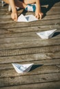 Child makes a paper boats sitting on wooden pier